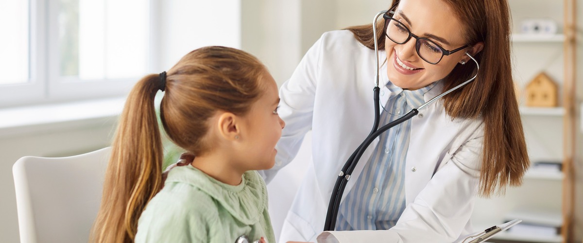 Ärztin behandelt mit Stethoskop ein Kind